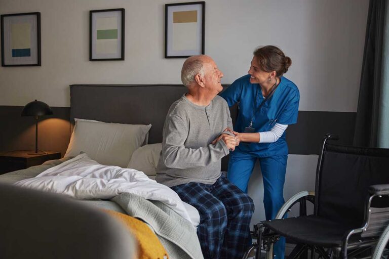 Family members and an older adult participate in a small assisted living activity around a table.